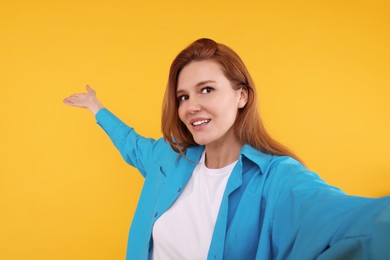 Photo of Beautiful woman taking selfie on orange background