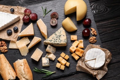 Photo of Flat lay composition with different types of delicious cheese on slate board
