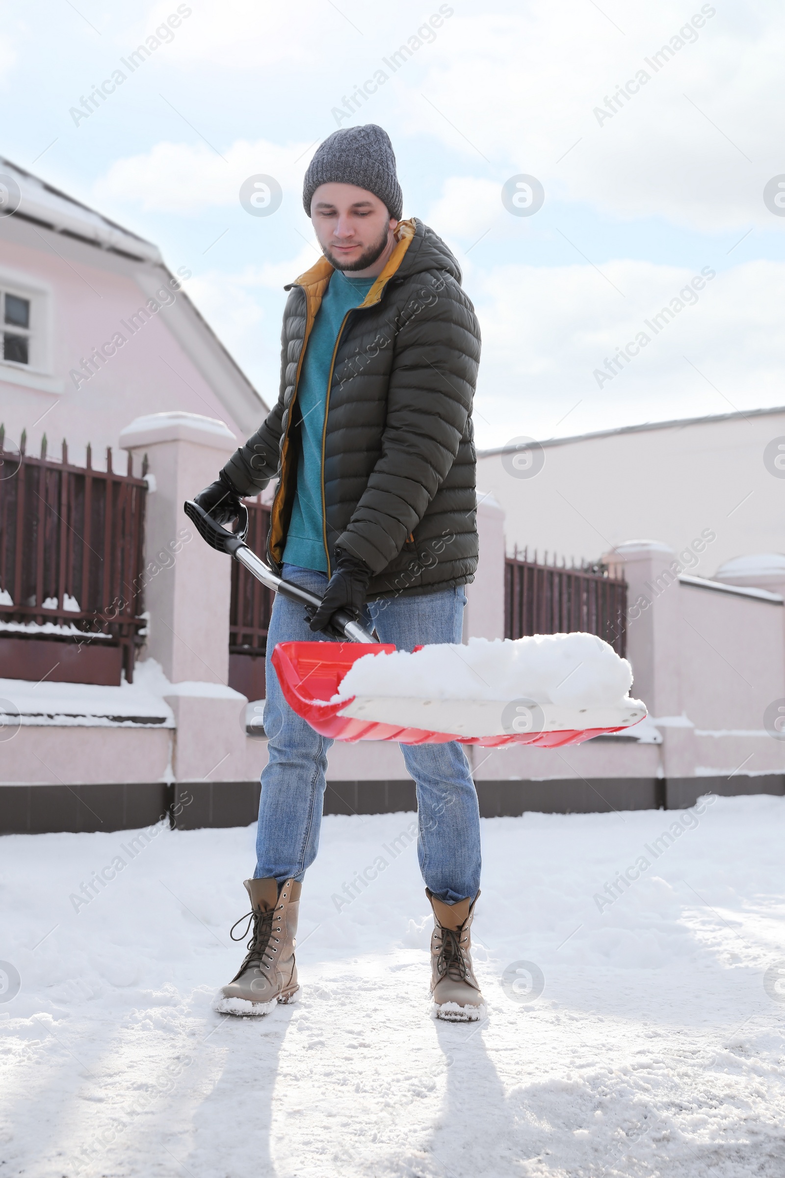 Photo of Young man shoveling snow outdoors on winter day