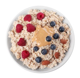 Photo of Tasty boiled oatmeal with berries, almonds and peanut butter in bowl isolated on white, top view