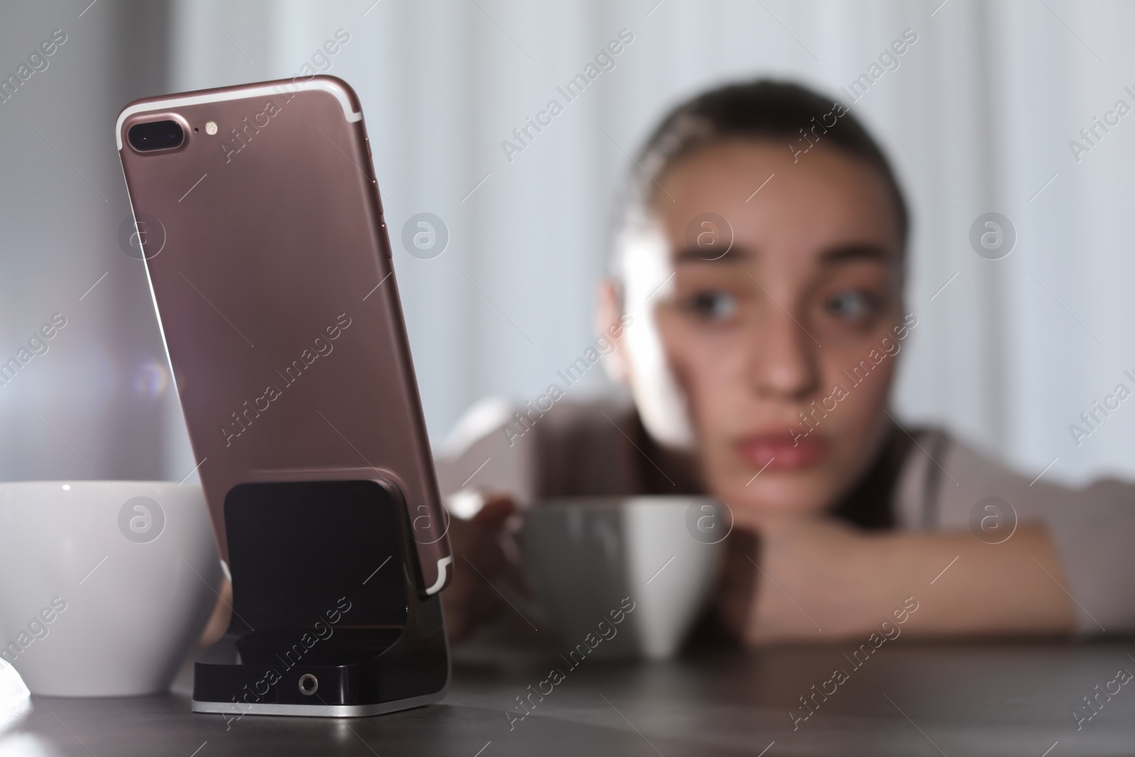 Photo of Lonely woman looking at smartphone on foreground, space for text