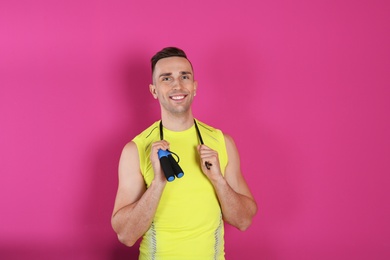 Photo of Portrait of young sportive man with jump rope on color background. Space for text