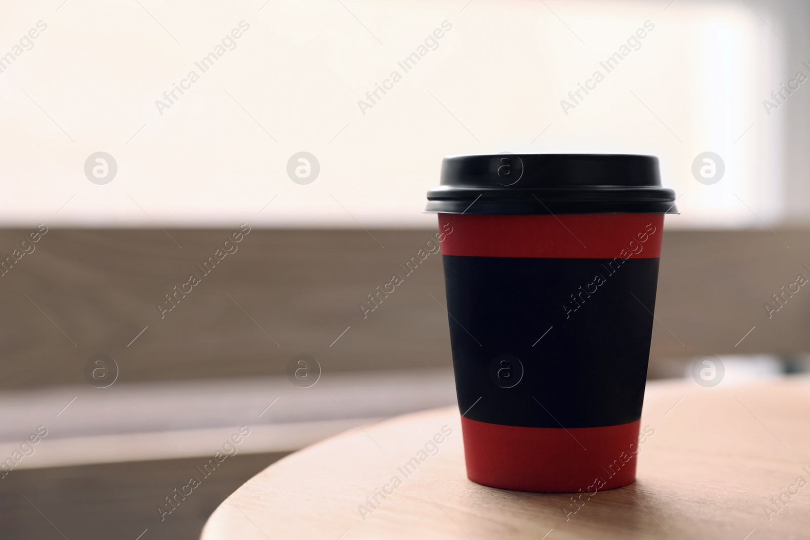 Photo of Hot coffee in takeaway paper cup on wooden table at cafe, space for text