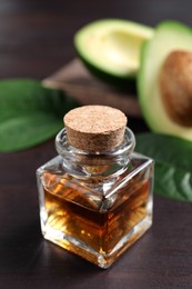 Photo of Bottle of avocado essential oil on wooden table. Space for text