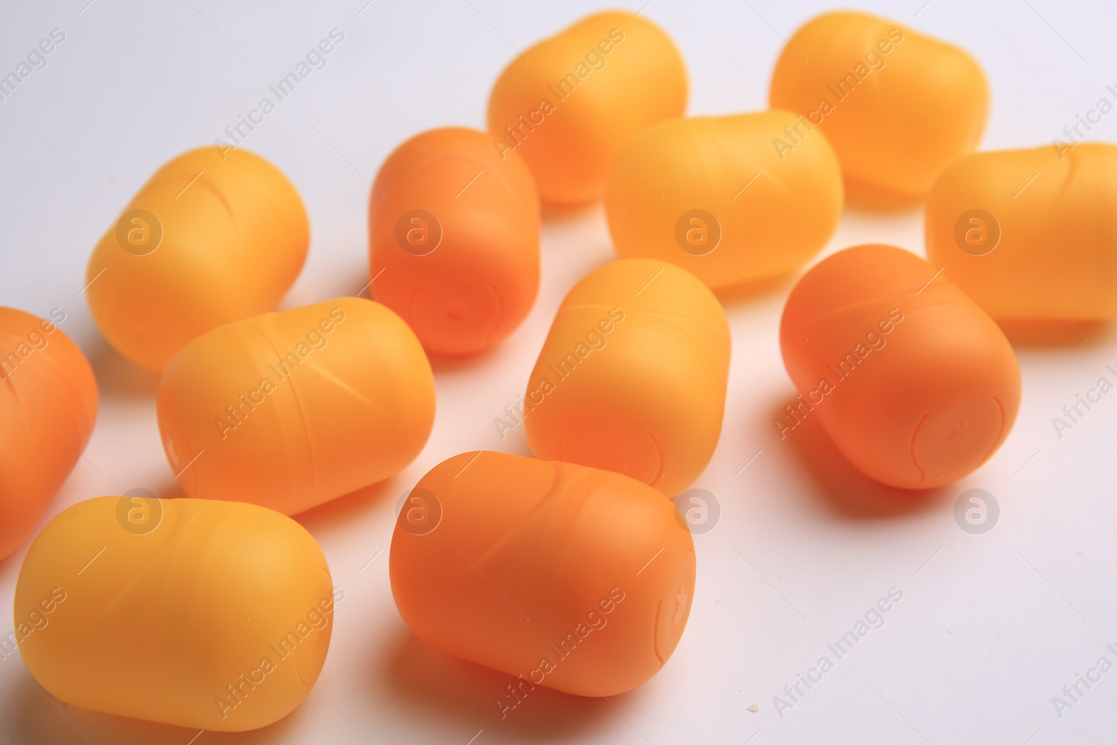 Photo of Sveti Vlas, Bulgaria - June 30, 2023: Orange plastic capsules from Kinder Surprise Eggs on white background, closeup