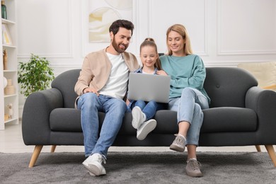 Happy family spending time together and using laptop on sofa at home