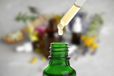 Little bottle with essential oil and dropper against blurred background 