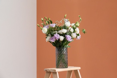 Photo of Bouquet of beautiful Eustoma flowers on wooden stand