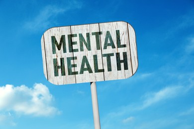 Image of Wooden sign with phrase Mental Health against blue sky on sunny day