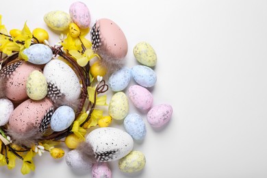 Photo of Decorative nest with many painted Easter eggs on white background, flat lay. Space for text