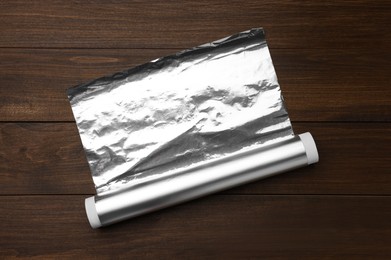 Photo of Roll of foil paper on wooden table, top view