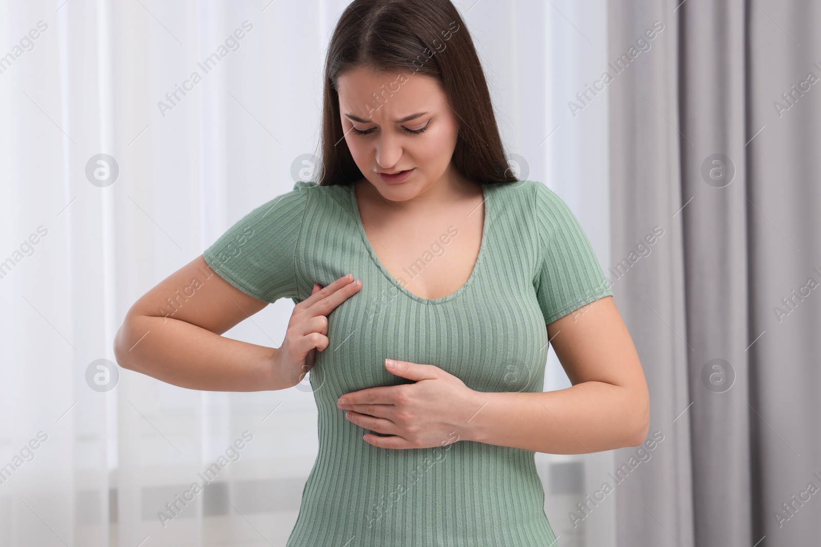 Photo of Mammology. Young woman doing breast self-examination at home