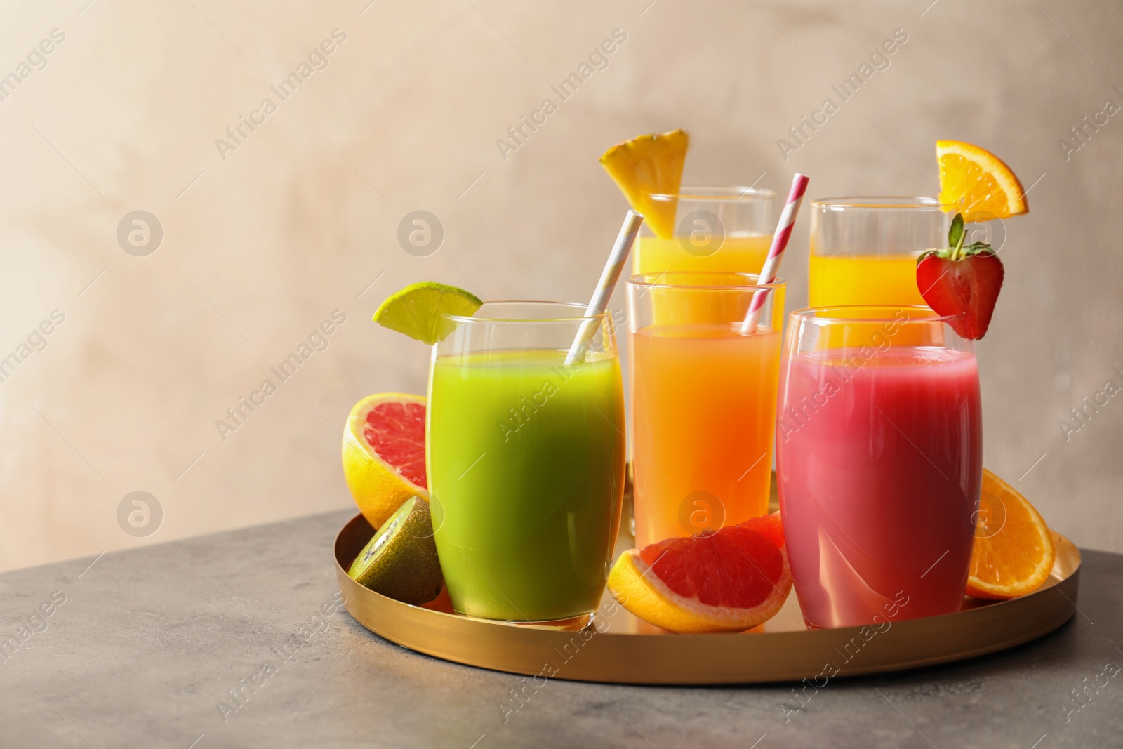 Photo of Tray with glasses of different juices and fresh fruits on table. Space for text