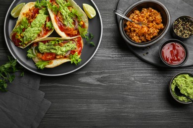 Photo of Delicious tacos with guacamole, meat and vegetables on wooden table, flat lay. Space for text