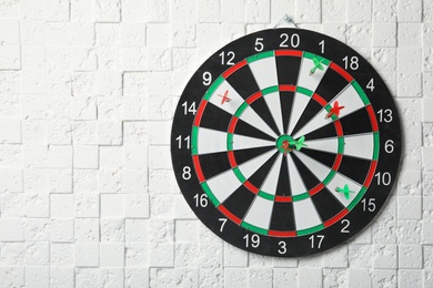 Photo of Arrows hitting dart board on white textured wall. Space for text