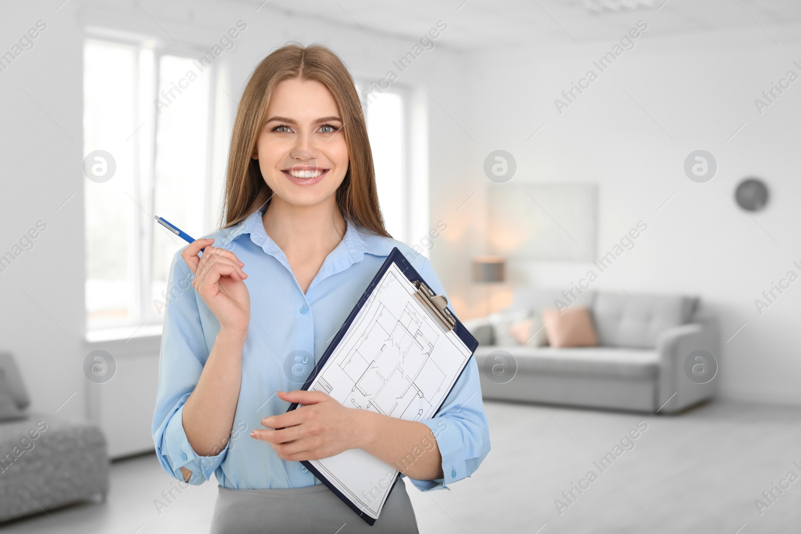 Photo of Beautiful real estate agent with clipboard indoors