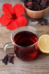 Photo of Cup of delicious hibiscus tea and lemon on wooden table