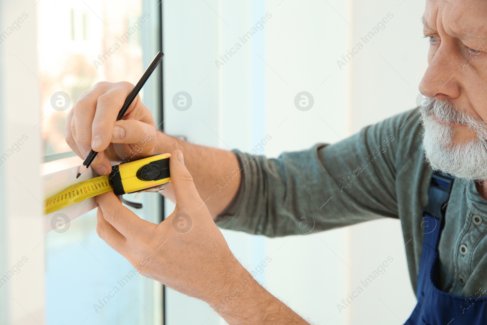 Photo of Service man measuring window for installation indoors