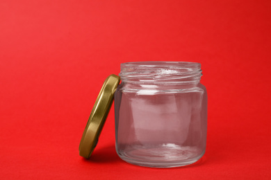 Photo of Open empty glass jar on red background