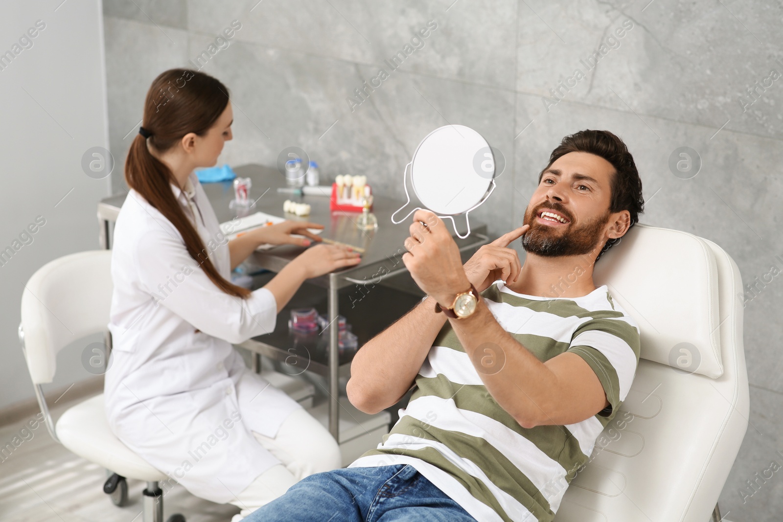 Photo of Man looking at his new dental implants in mirror indoors