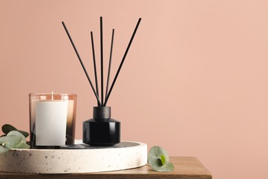 Photo of Composition with aromatic reed air freshener on wooden table near pink wall, space for text