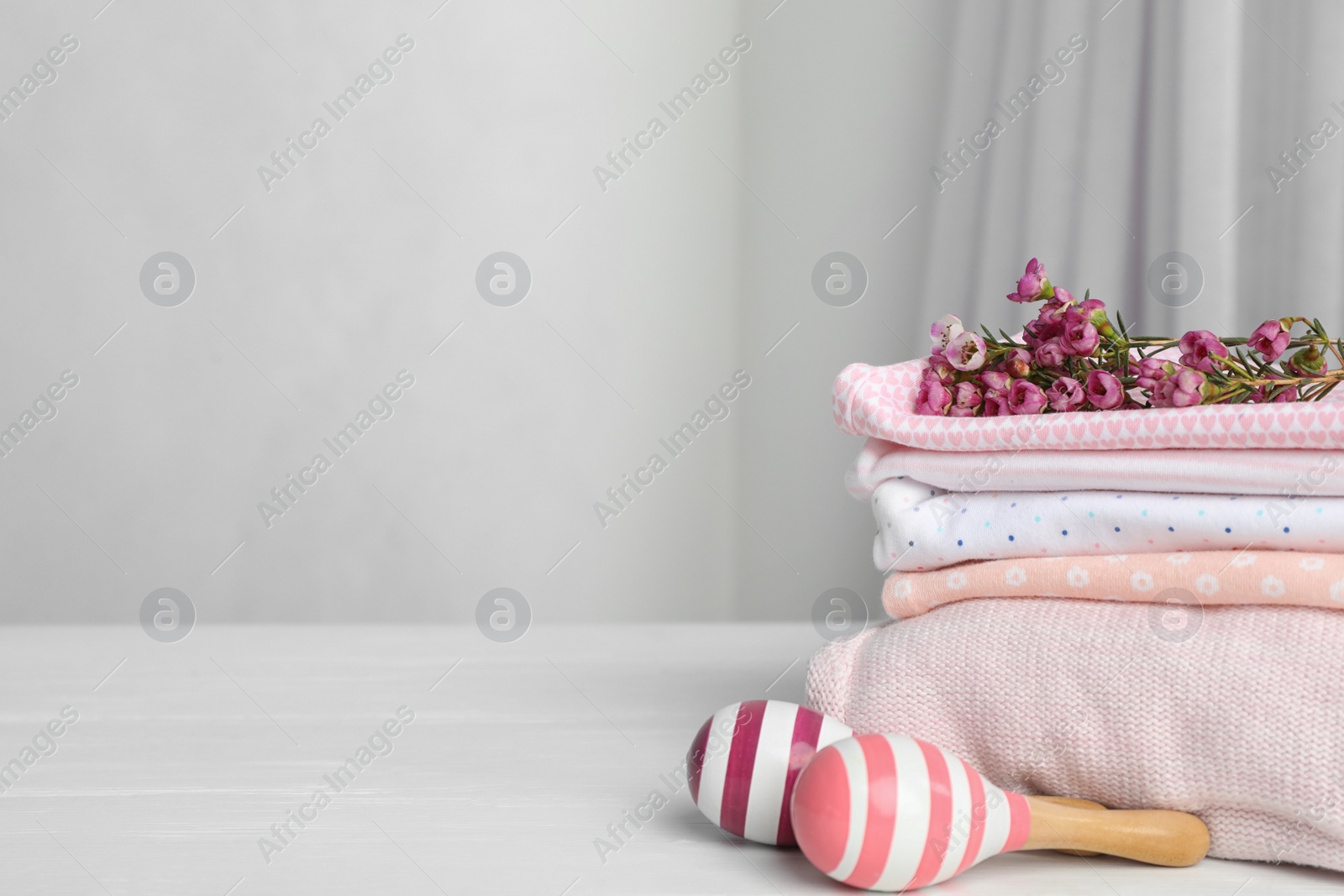Photo of Composition with maracas and child's clothes on  white wooden table, space for text