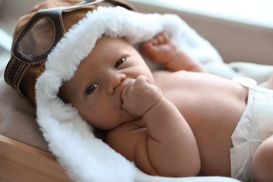 Cute newborn baby in aviator hat lying on blanket, closeup