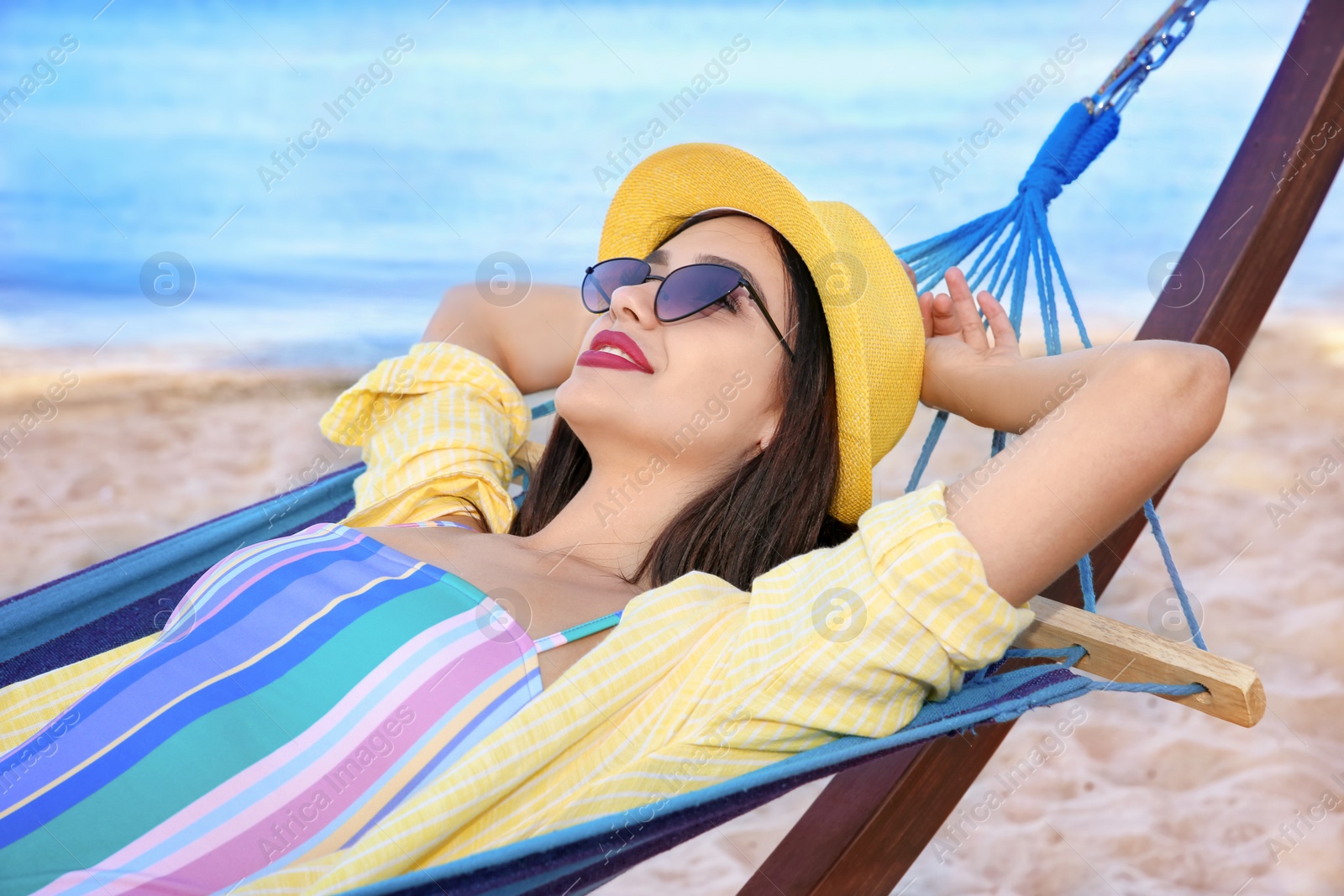 Photo of Young woman relaxing in comfortable hammock at seaside