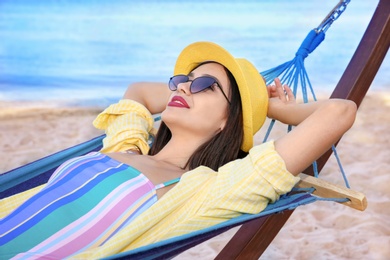 Young woman relaxing in comfortable hammock at seaside