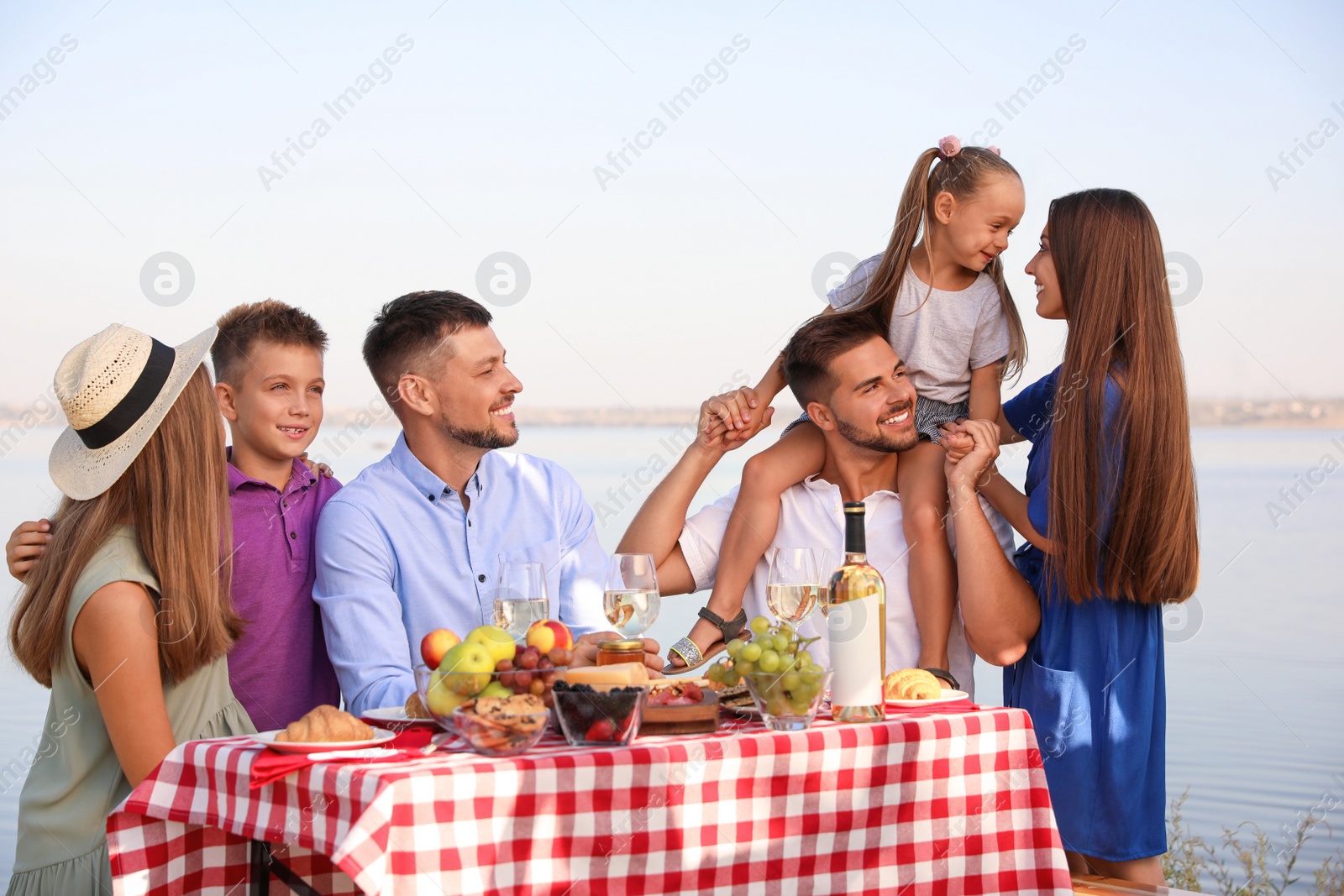 Photo of Happy families with little children having picnic at riverside