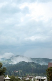 Picturesque view of village near mountains in foggy morning