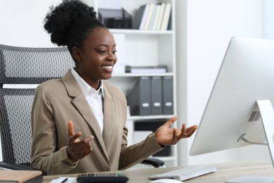 Professional accountant having video chat via computer at wooden desk in office