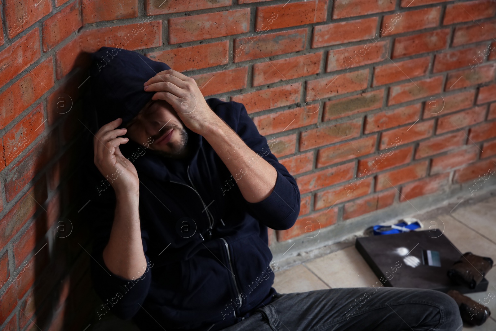 Photo of Young addicted man near brick wall after using drugs