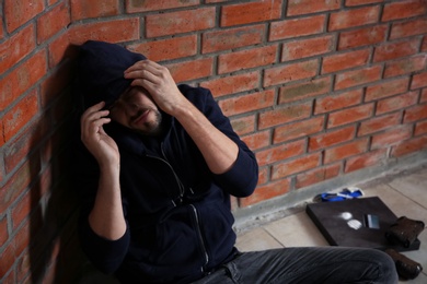 Photo of Young addicted man near brick wall after using drugs