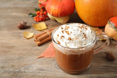 Glass cup with tasty pumpkin spice latte on wooden table, space for text