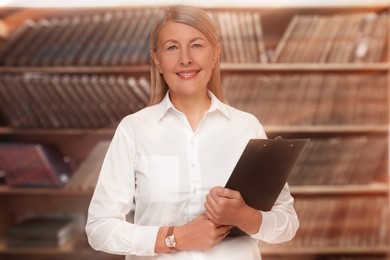 Lawyer, consultant, business owner. Confident woman with clipboard smiling indoors