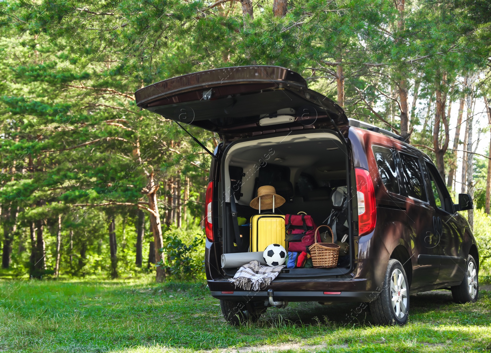 Photo of Van with camping equipment in trunk outdoors