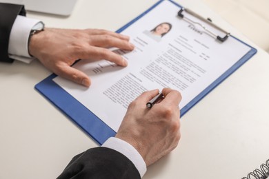 Photo of Human resources manager reading applicant's resume at table, closeup