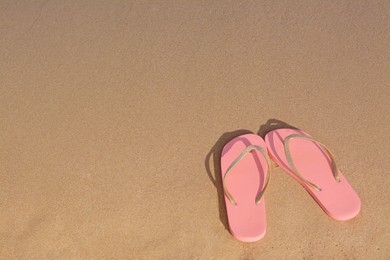 Photo of Stylish flip flops on sandy beach, above view. Space for text