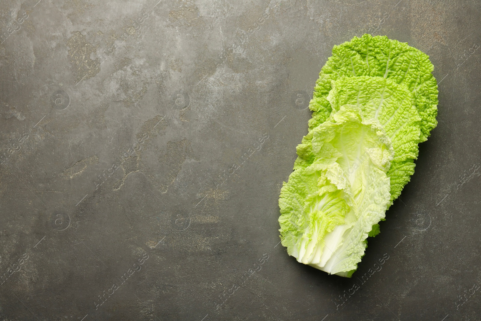 Photo of Fresh Chinese cabbage leaves on gray textured table, top view. Space for text