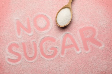 Photo of Words No Sugar and wooden spoon on pink background, top view