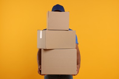 Courier with stack of parcels on orange background