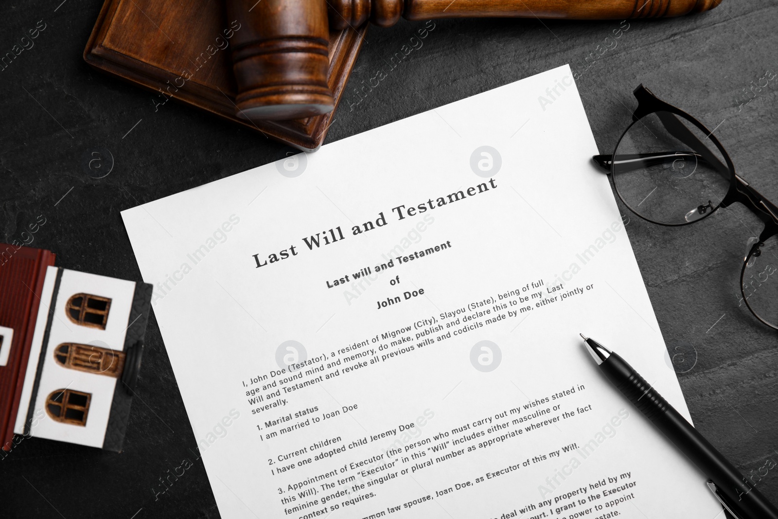 Photo of Last will and testament near house model, glasses, gavel on black table, flat lay