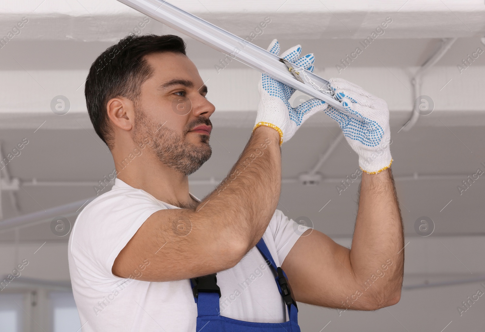 Photo of Ceiling light. Electrician installing led linear lamp indoors