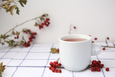 Cup with hawthorn tea and berries on table. Space for text