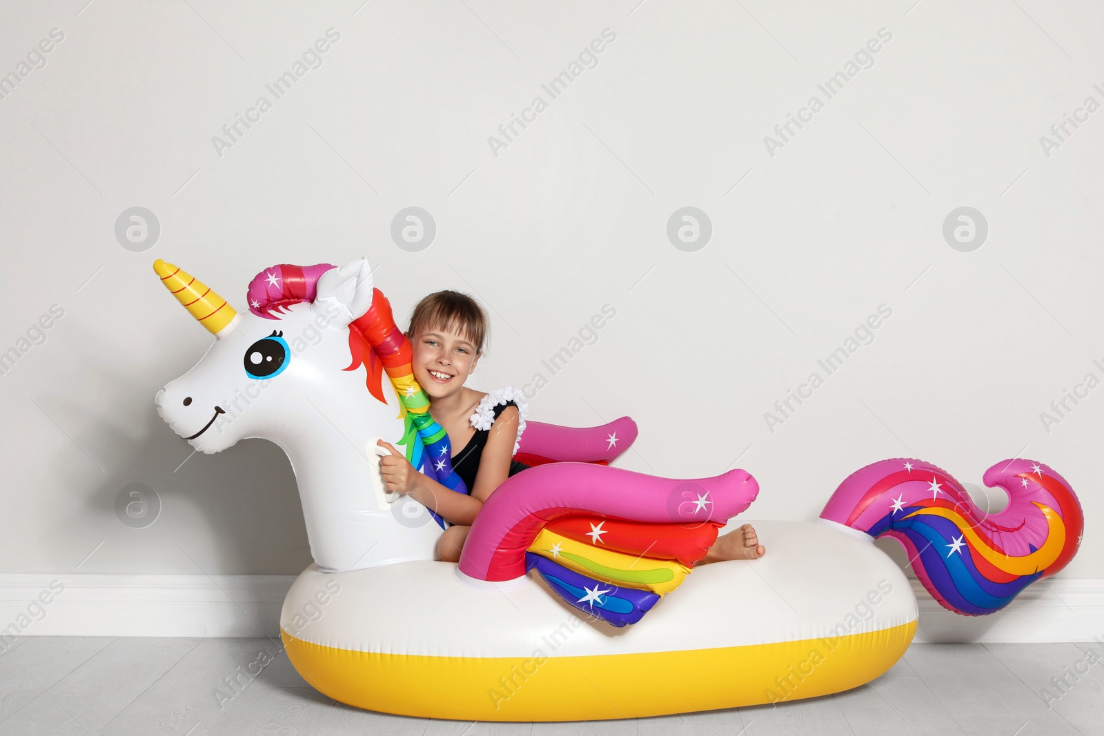 Photo of Cute little girl on bright inflatable ring near light wall