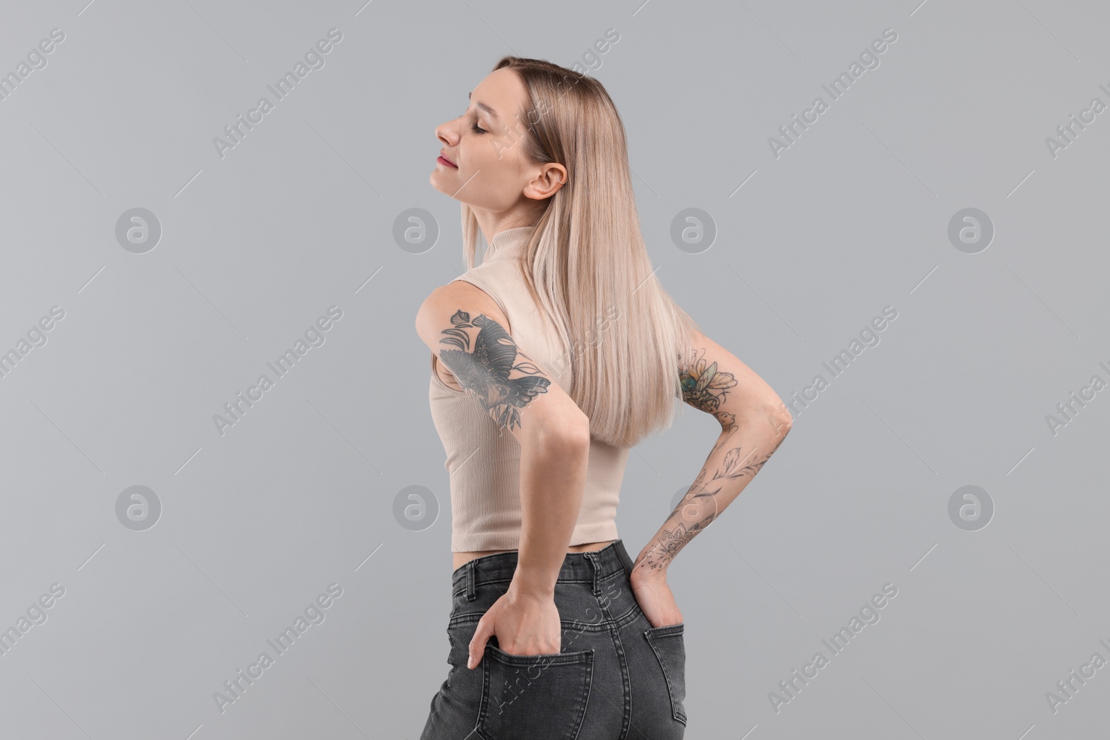 Photo of Portrait of beautiful tattooed woman on gray background