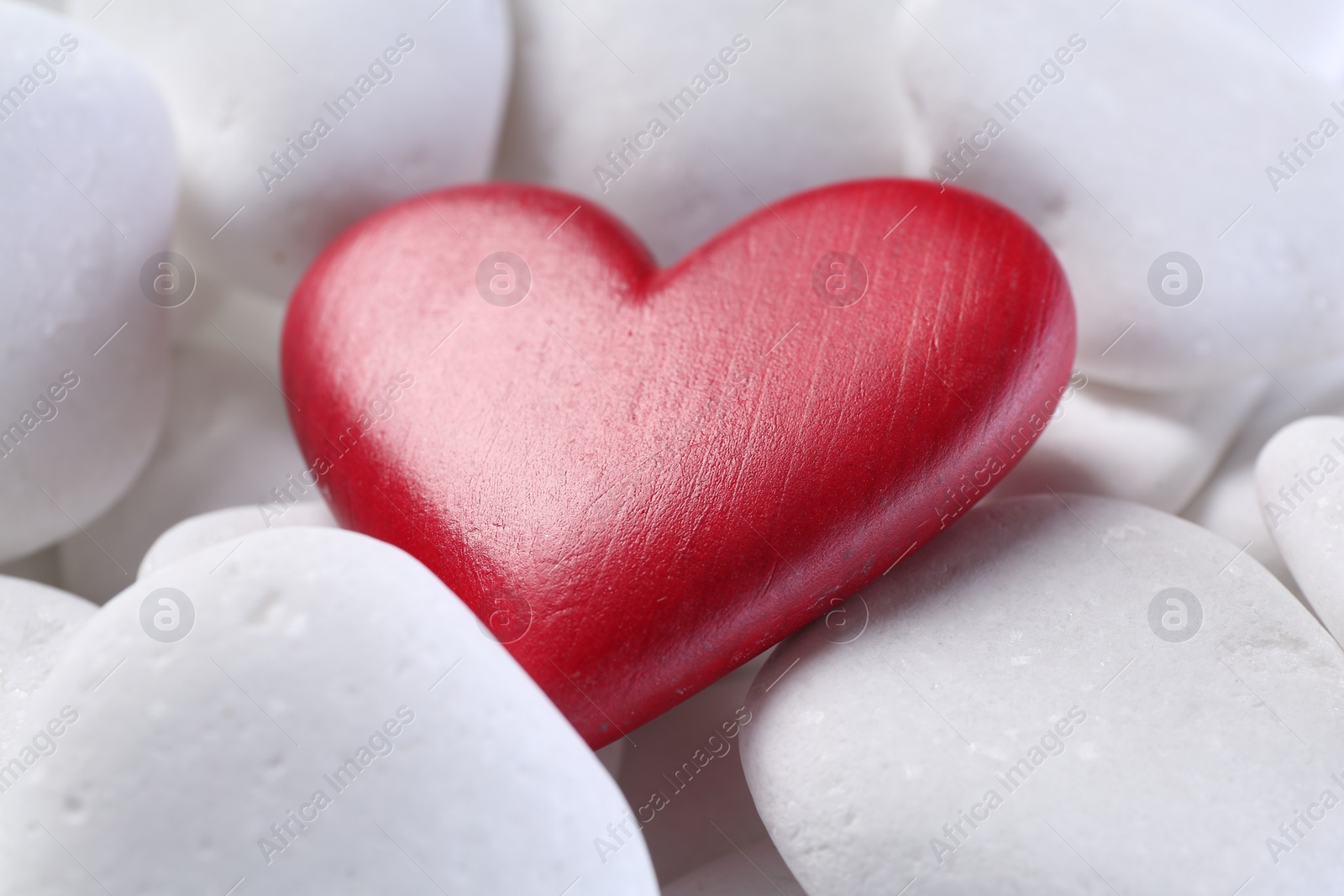 Photo of Decorative heart on white pebble stones, closeup