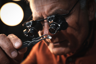 Photo of Professional jeweler evaluating beautiful gemstone, closeup view