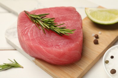 Photo of Raw tuna fillet with rosemary and spices on white table, closeup
